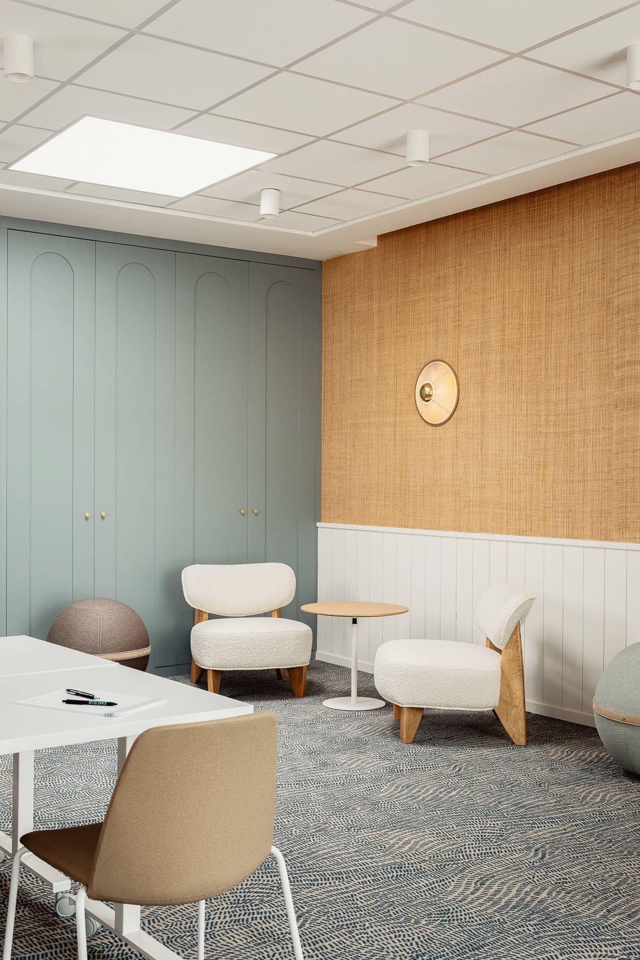 Petit espace bureau avec placards bleu-gris, fauteuils en bouclette blanche et table de travail